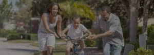 mother and father teaching child to ride a bike